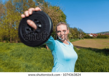 Young woman lifts weights in a sport dress