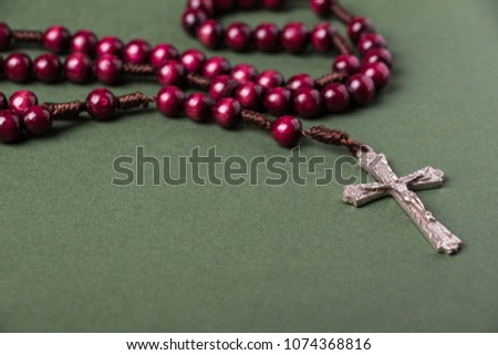 Pink Rosary on a green background with space for writing Christian cross. 