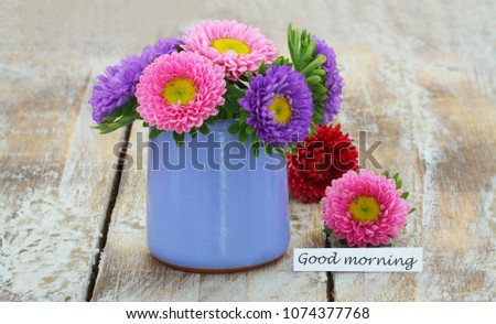 Good morning card with colorful daisy flowers in blue vase on rustic wood
