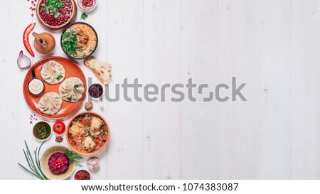 View from above of georgian cuisine on white wooden table. Banner traditional georgian food - khinkali, kharcho, chahokhbili, phali, lobio and local sauces. Top view. Copy space for text Royalty-Free Stock Photo #1074383087