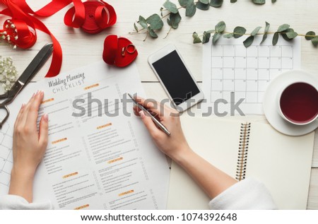 Wedding arrangement background. Female hands preparing for marriage, smartphone, paper calendars and planners, top view. Bridal wallpaper with copy space on to do list