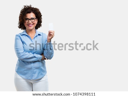 Middle aged woman smiling confident, offering a business card, has a thriving business, copy space to write whatever you want