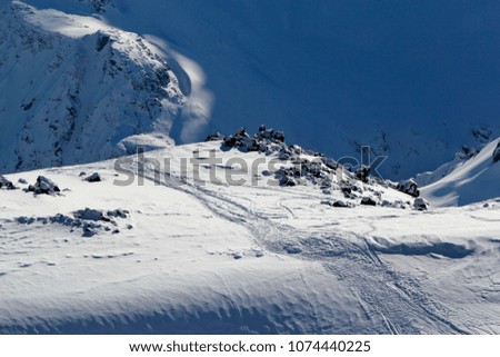 High mountains off-piste slopes for freeride with traces of skis and snowboards, sunny winter day, Caucasus Mountains, Elbrus, Russia