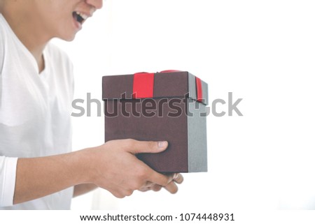 Cropped image of asian romantic guy with white shirt hold a present with red ribbon on his hands with white background and copy space. Surprise on anniversary,newyear,valentine or christmas concept.