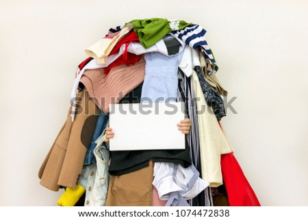 Empty copy space on the board with pile of messy clothing on the background Royalty-Free Stock Photo #1074472838