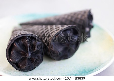 Trendy food. Black ice cream in traditional portioned black ice cream cones. Copy space. Soft focus.