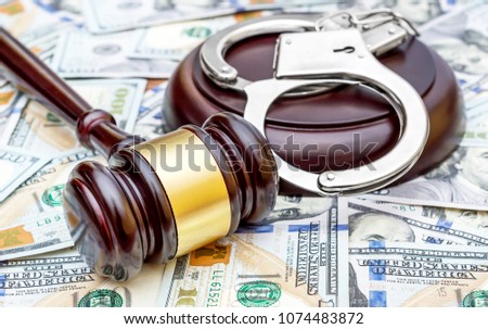 Judge's gavel with handcuffs on the background of dollar bills.  Royalty-Free Stock Photo #1074483872