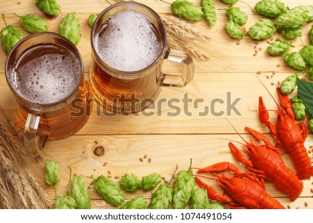 Glass beer with crawfish, hop cones and wheat ears on light wooden background. Beer brewery concept. Beer background. top view