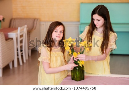 Beautiful girls at dawn indoors. Children with flowers.