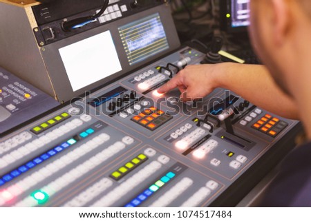 TV editor working with audio video mixer in a television broadcast studio desk station