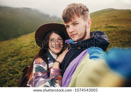 happy hipster couple making selfie on top of sunny mountains. summer vacation. space for text. atmospheric moment. travel and wanderlust concept. stylish man and woman traveling
