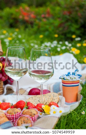 Two glasses of wine and strawberries. Picnic in a clearing with flowers. Spring in the Netherlands. Place for text. holidays
