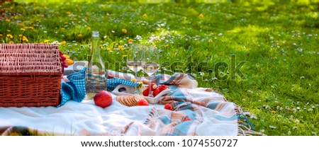 picnic basket and food. A bottle of wine and two glasses. Romanica. Green meadow with flowers. Spring in the Netherlands. Holidays. Top view. Place for text
