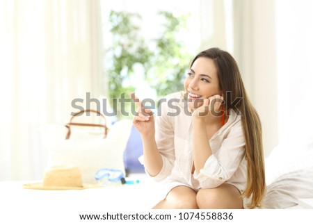 Hotel guest pointing at side sitting on a bed on summer holidays