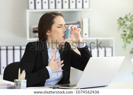 Asmathic executive having an asthma attack inhaling with a inhaler at office Royalty-Free Stock Photo #1074562436