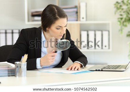 Suspicious executive analyzing meticulously a document at office Royalty-Free Stock Photo #1074562502