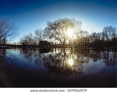 Reflection of trees in spring water river at sunset time, silhouette of car and people at nature background, amazing mystic springtime landscape, toned
