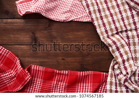 Background of brown rustic wooden table with different colorful kitchen towels. Top view