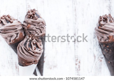 Double Chocolate Ice Creams with Black Waffle Cones on Wooden Background