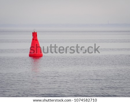 Red buoy as a navigation mark in the calm sea 