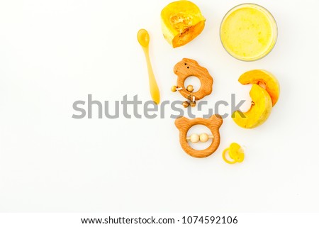 Healthy food for little baby. Puree with pumpkin near pacifier and toys on white background top view copy space