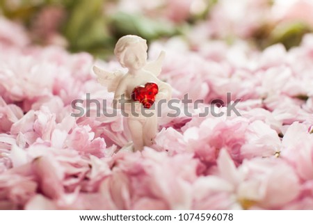 Angel with heart. White statue. Statue of angel. Branch of sakura with flowers and leaves. Cherry blossom , pink sakura flower isolated in white background.