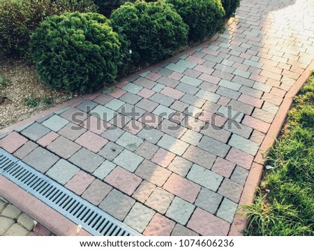 Nested pavers of various colors, around the grass is green, chic garden