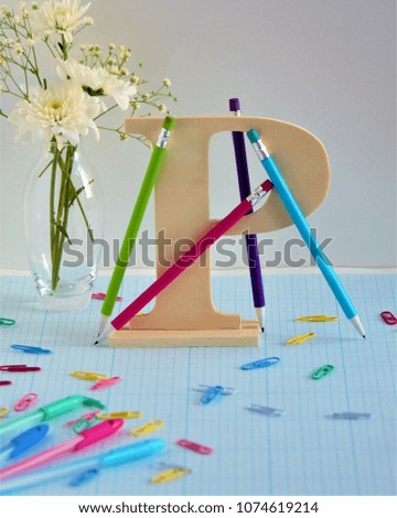 Hello School. Hello, September. Stationery on the background of the letter P (pen, pencil). In the background is a bouquet of chrysanthemums. Can be used as a background image that copies space.