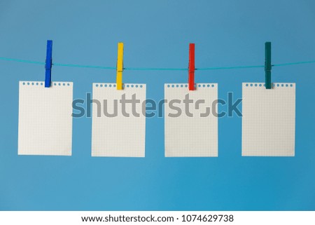 Timetable concept. Blank white note pages pinned to rope with clothespins on blue background.