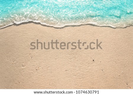 Soft waves with foam of blue ocean on the sandy beach summer background