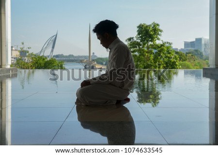 Young Muslim man performing pray in Islamic attire. 