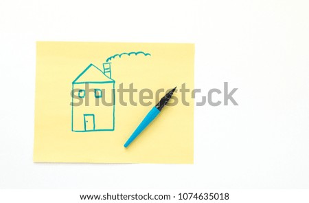 blue marker pen next to a child's drawing of a house on yellow paper isolated on white with copy space