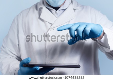 Photo of lab assistant in medical outfit holding and pointing at tablet.