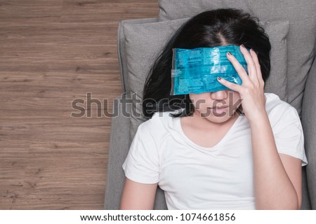 Top view of Asian woman with cold pack on her forehead for relief fever headaches and migraines Royalty-Free Stock Photo #1074661856
