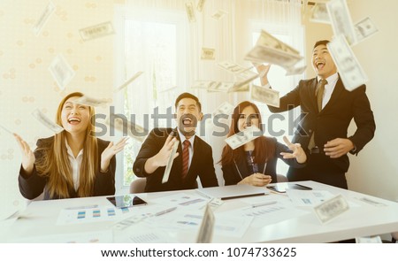 Happy emotional Asian people celebrate success Business screaming under money rain falling down dollar bills banknotes to become rich, Modern office background,Business Financial Money freedom concept