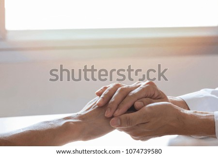 Doctor holding a patient hand to give empathy and support in medical office