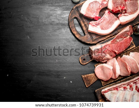 Different types of raw pork meat and beef. On the black chalkboard. Royalty-Free Stock Photo #1074739931