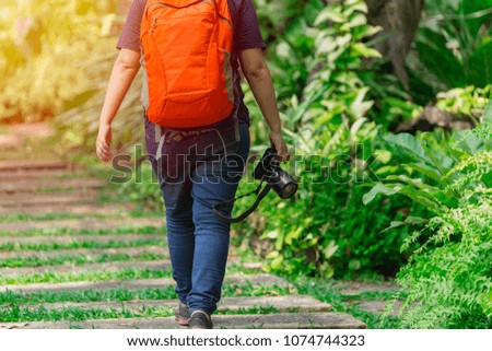 Nature photographer walking with camera gear in the park to find insect subject and explorer