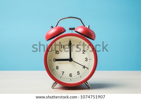 Red vintage alarm clocks on wooden table and light blue background wall