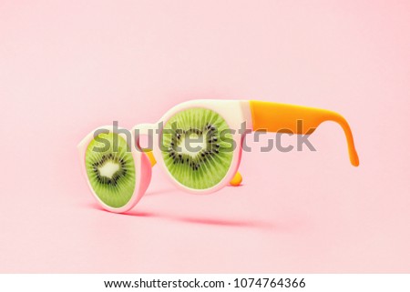 Beach sunglasses concept with kiwi on pink background