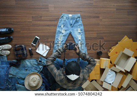 Top view of men shooting take a photo jeans pants and fashion accessories on wooden floor with postal parcel, Selling online ideas concept