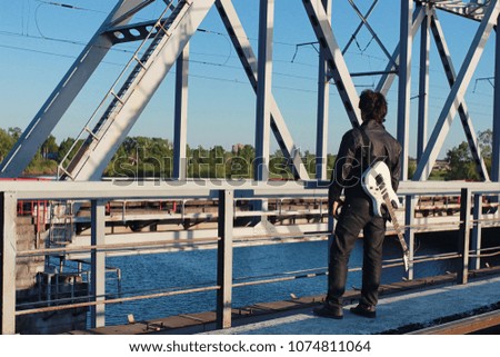 a man with an electric guitar in the industrial landscape outdoors