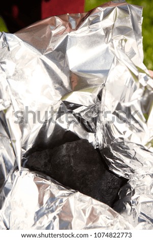 Man packing meteorite found on spring meadow to aluminium foil