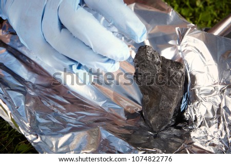 Man packing meteorite found on spring meadow to aluminium foil