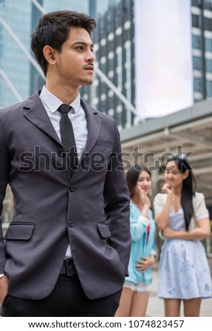 Young smart businessman handsome and behind two girl taking gossip