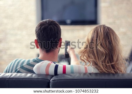 Happy young couple relaxing and watching TV at home. Royalty-Free Stock Photo #1074853232