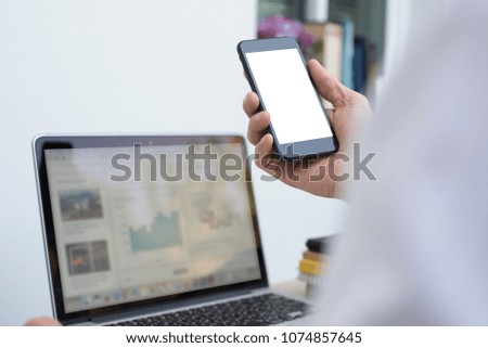 Mock up, businessman holding blank screen  mobile smart phone, working on laptop computer in office, internet connecting, web design, smartphone application advertising