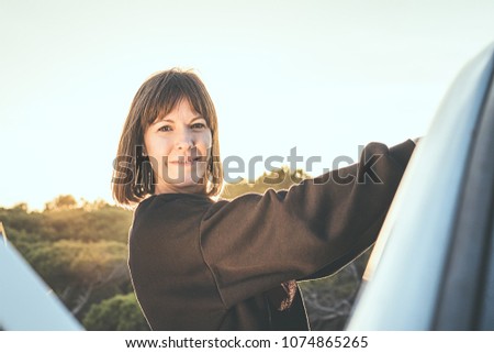 Young girl smiling, holding on to the door of a car... Concept of travel and freedom