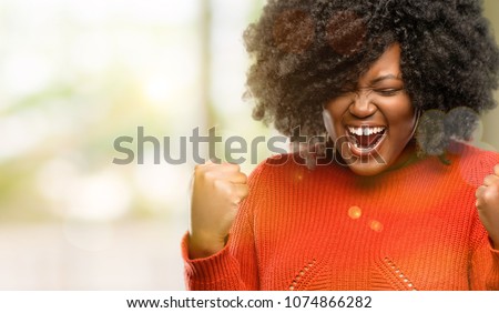 Beautiful african woman happy and excited celebrating victory expressing big success, power, energy and positive emotions. Celebrates new job joyful, outdoor Royalty-Free Stock Photo #1074866282