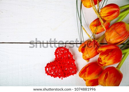Bouquet of tulips and red heart on a white wooden background. Greeting card for Valentine's Day, Wedding or Birthday